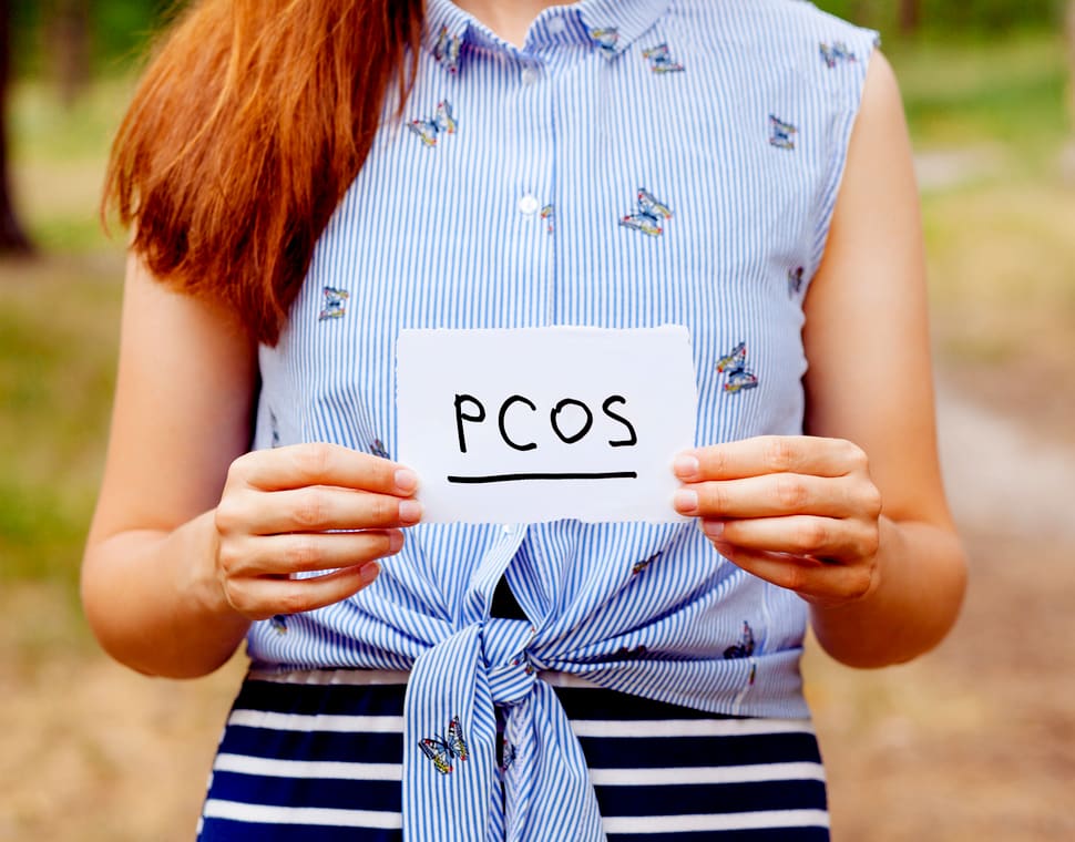 Woman holding a piece of paper with PCOS diagnosis