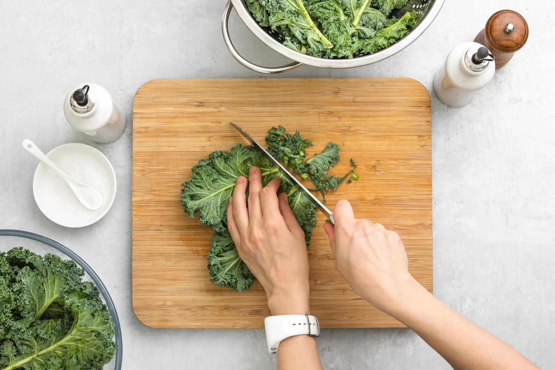 Fresh kale leaves are cut by woman's hands on a cutting board