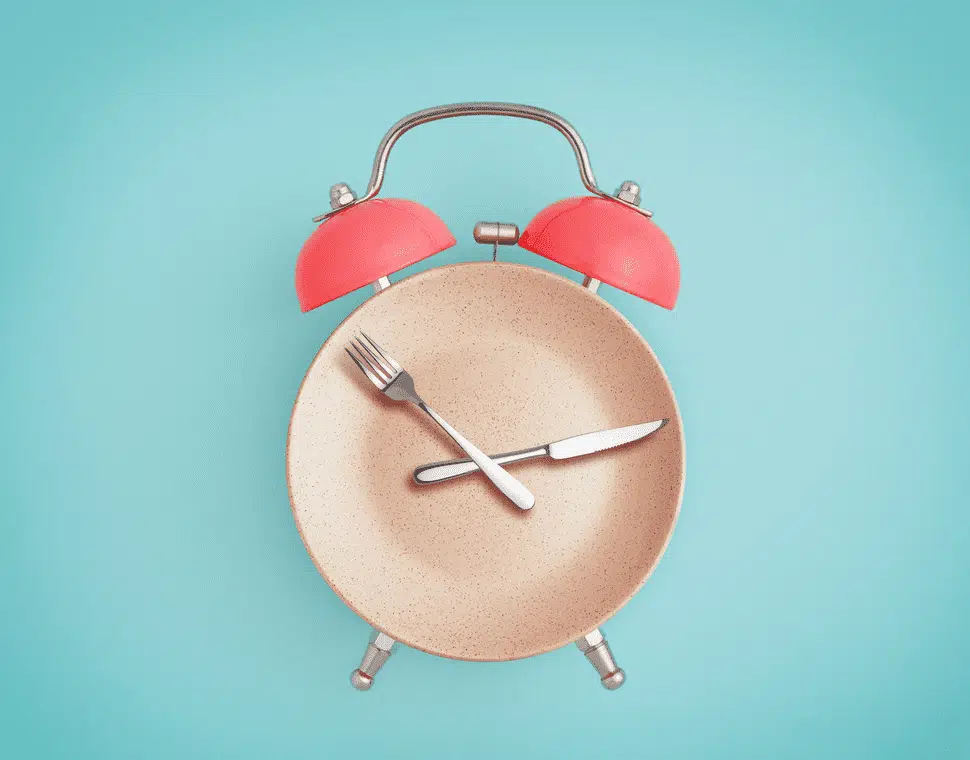 Pink clock on plate symbolizing fasting for fertility